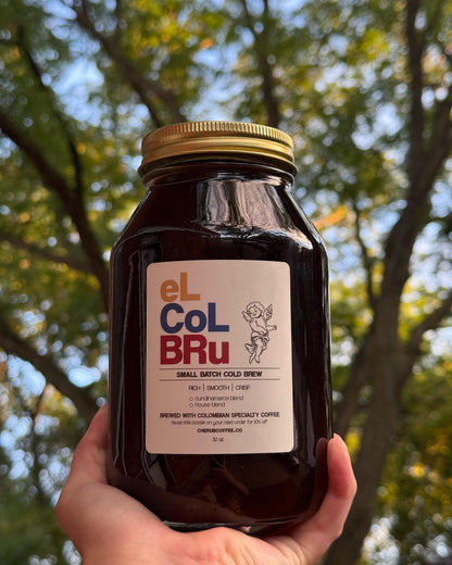 Jar of El Col Bru held in front of trees.